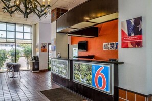 A hotel reception area with a counter, a television, and a sign indicating room number 6.