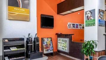 A reception area with a coffee machine, a bulletin board, and a television.