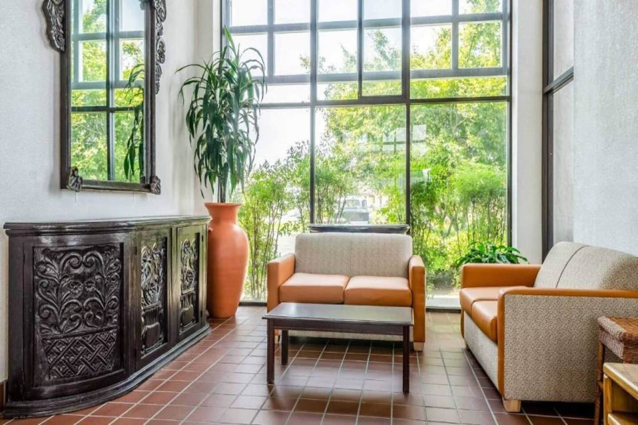 Una habitación con un ventanal grande, un sofá, una silla y un mueble decorativo.