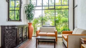 Una habitación con un ventanal grande, un sofá, una silla y un mueble decorativo.