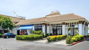 A hotel with a tiled roof, a covered entrance, and a parking lot.