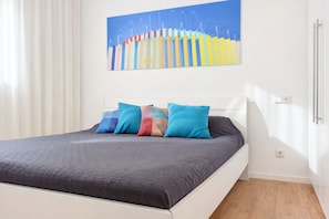 Una cama con colcha gris oscuro, cabecera blanca y almohadas coloridas.