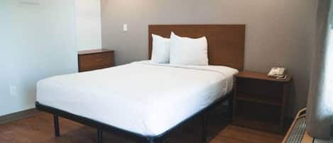 Una habitación de hotel estándar con una cama individual, una mesita de noche, un teléfono y un radiador.