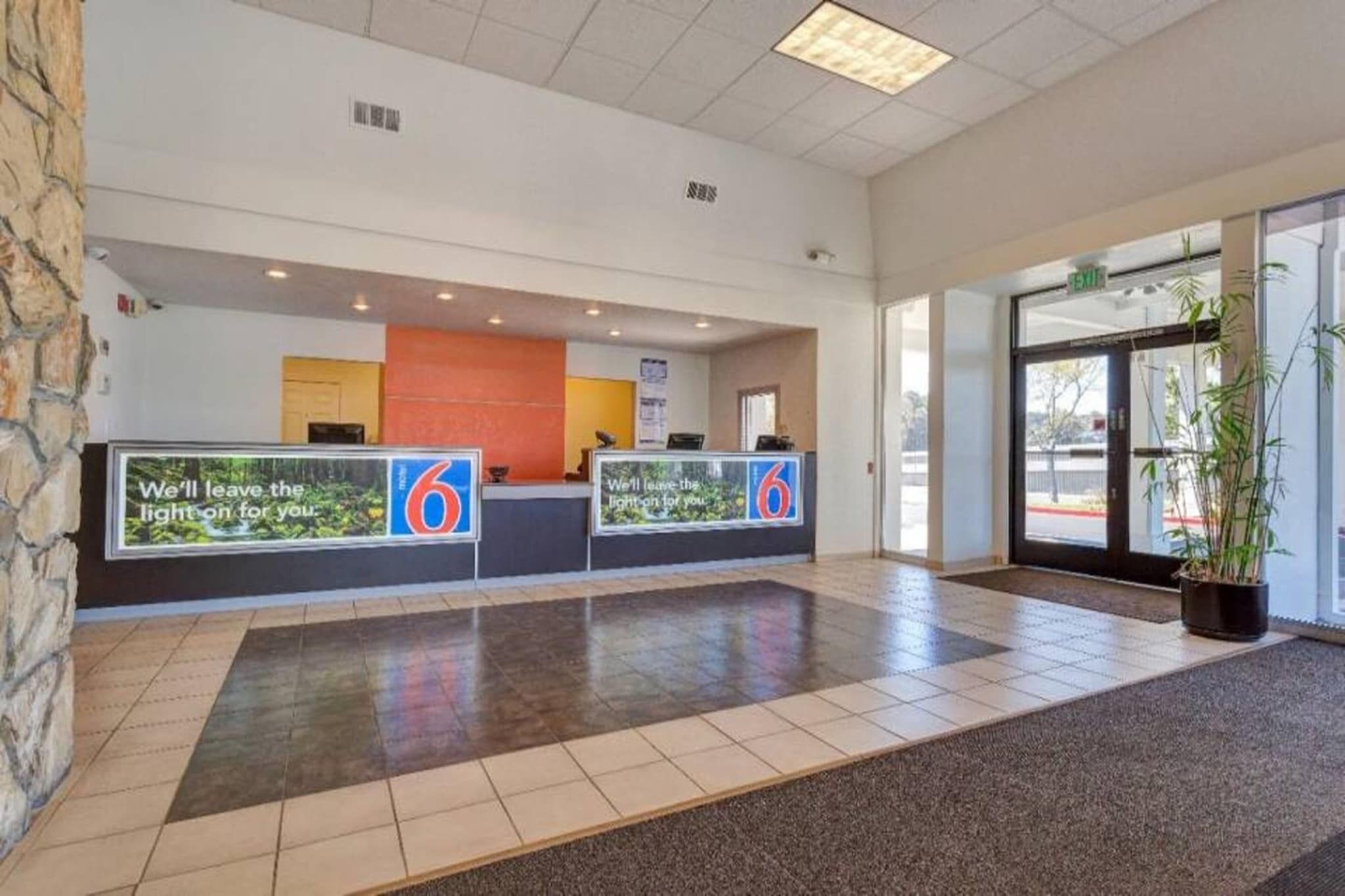 A reception area with a counter, a sign with the number 6, and a potted plant.