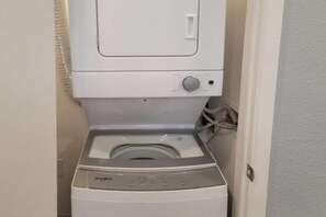 A compact washer and dryer unit in a small laundry room. - 1 Full Bed | ADA/RI Shower (Las Vegas)