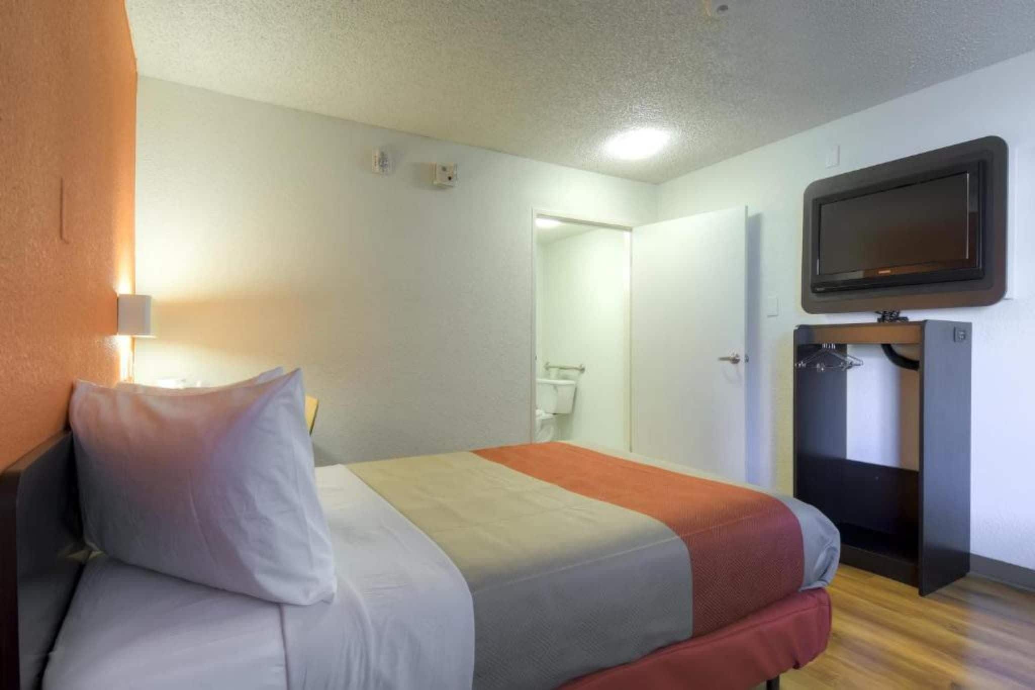 Ein Hotelzimmer mit Bett, Fernseher und Kleiderschrank.
