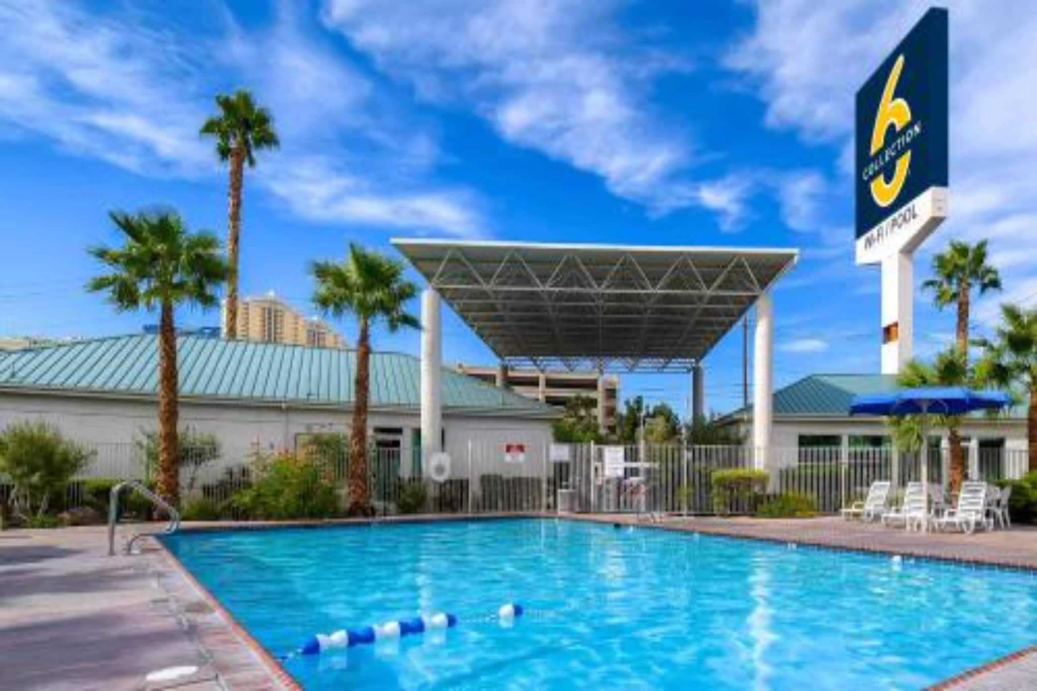 Ein Pool mit überdachtem Bereich, Palmen und einem Hotelschild.