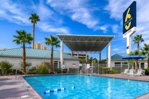 Ein Pool mit überdachtem Bereich, Palmen und einem Hotelschild.