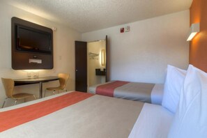 Een hotelkamer met twee bedden, een bureau en een televisie.