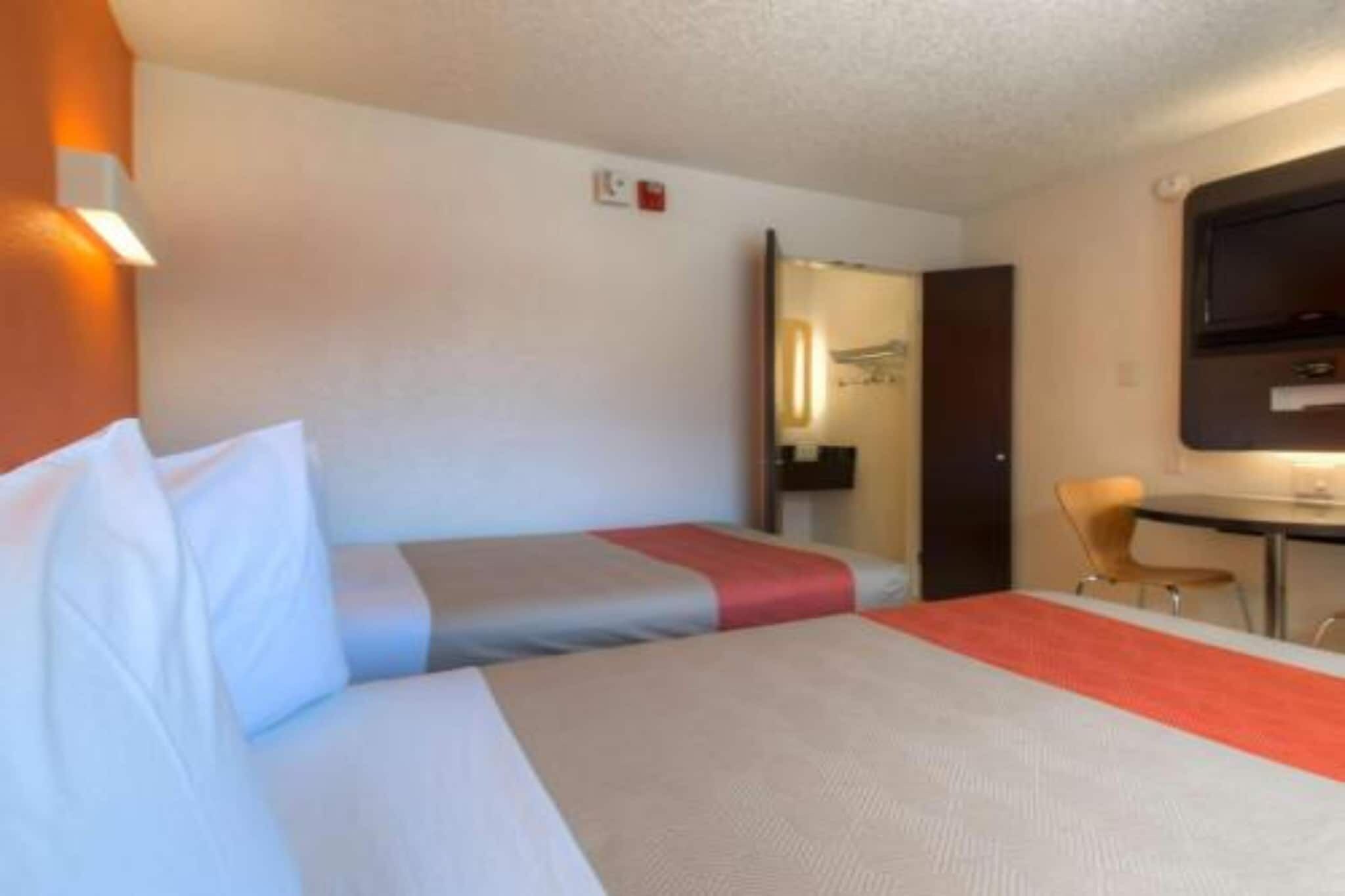 A hotel room with a bed, a desk, and a TV.