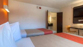 A hotel room with a bed, a desk, and a TV.