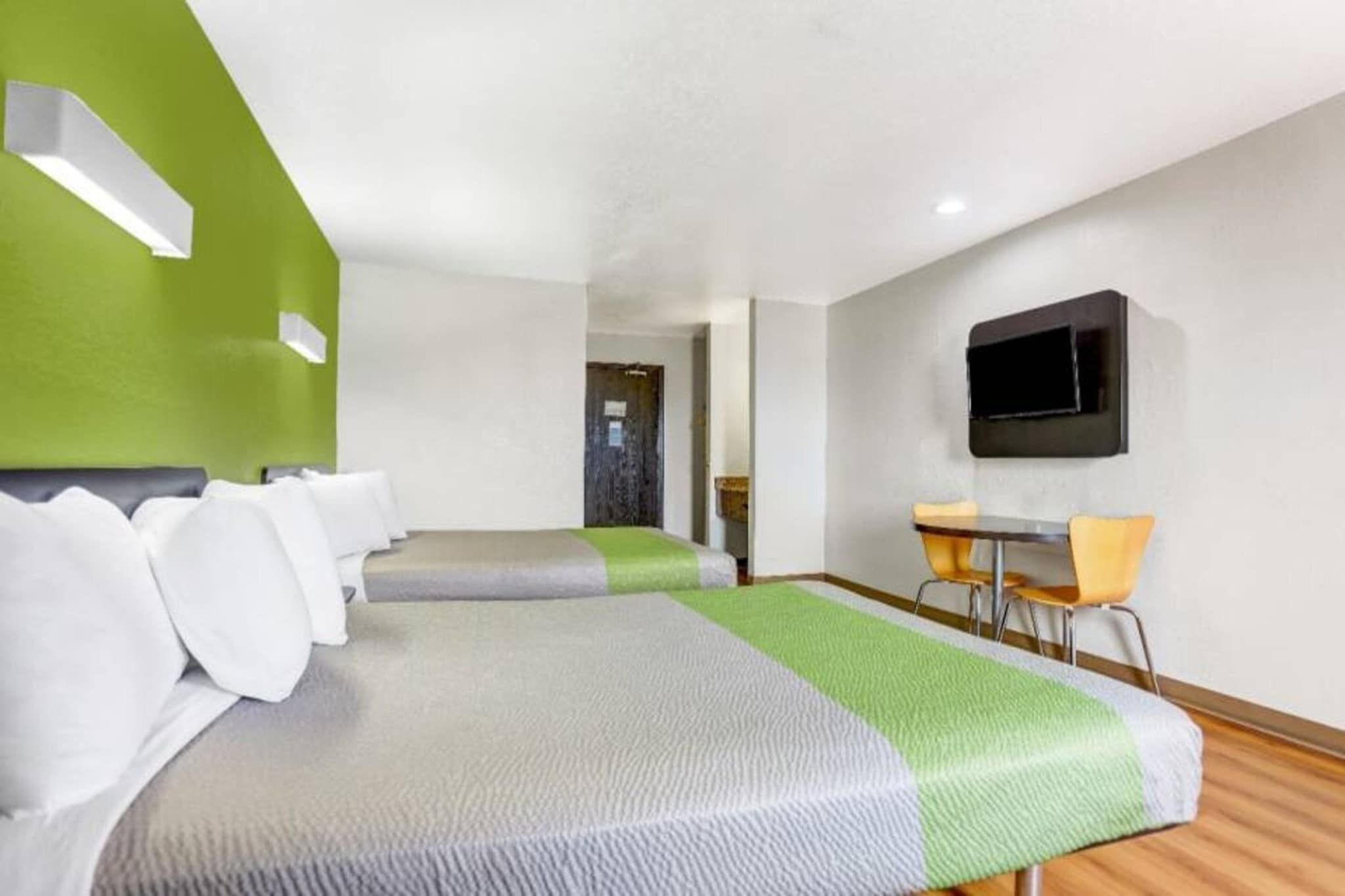 A hotel room with two beds, a desk, and a television.