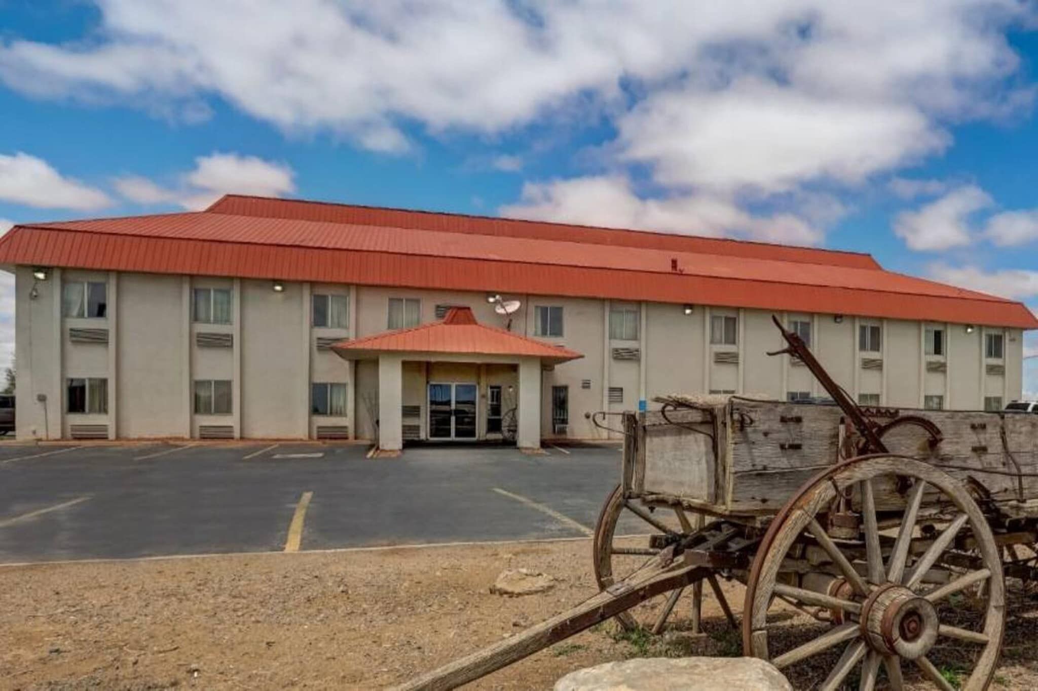 A building with a red roof, a covered entrance, and a parking lot.