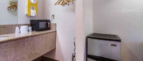 A kitchenette with a microwave, a refrigerator, and a countertop with a sink.