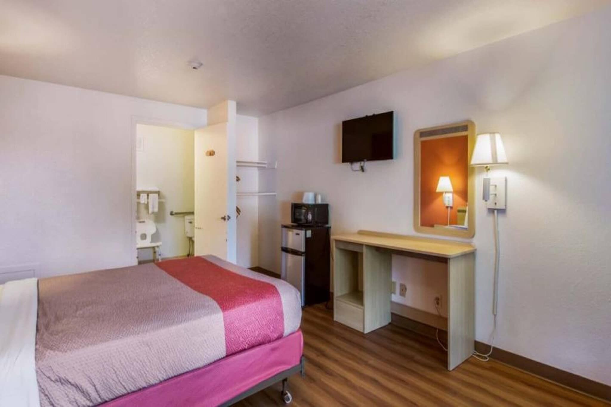 Une chambre d’hôtel avec un lit, un bureau, une télévision et une lampe.