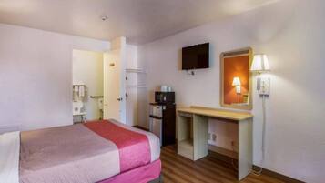 Une chambre d’hôtel avec un lit, un bureau, une télévision et une lampe.