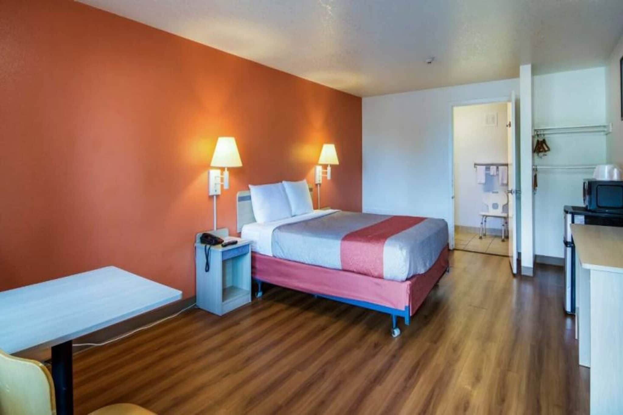 Una habitación de hotel con cama, mesitas de noche, lámparas, escritorio y una silla.