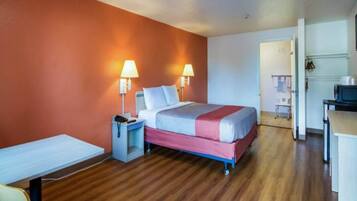 Una habitación de hotel con cama, mesitas de noche, lámparas, escritorio y una silla.