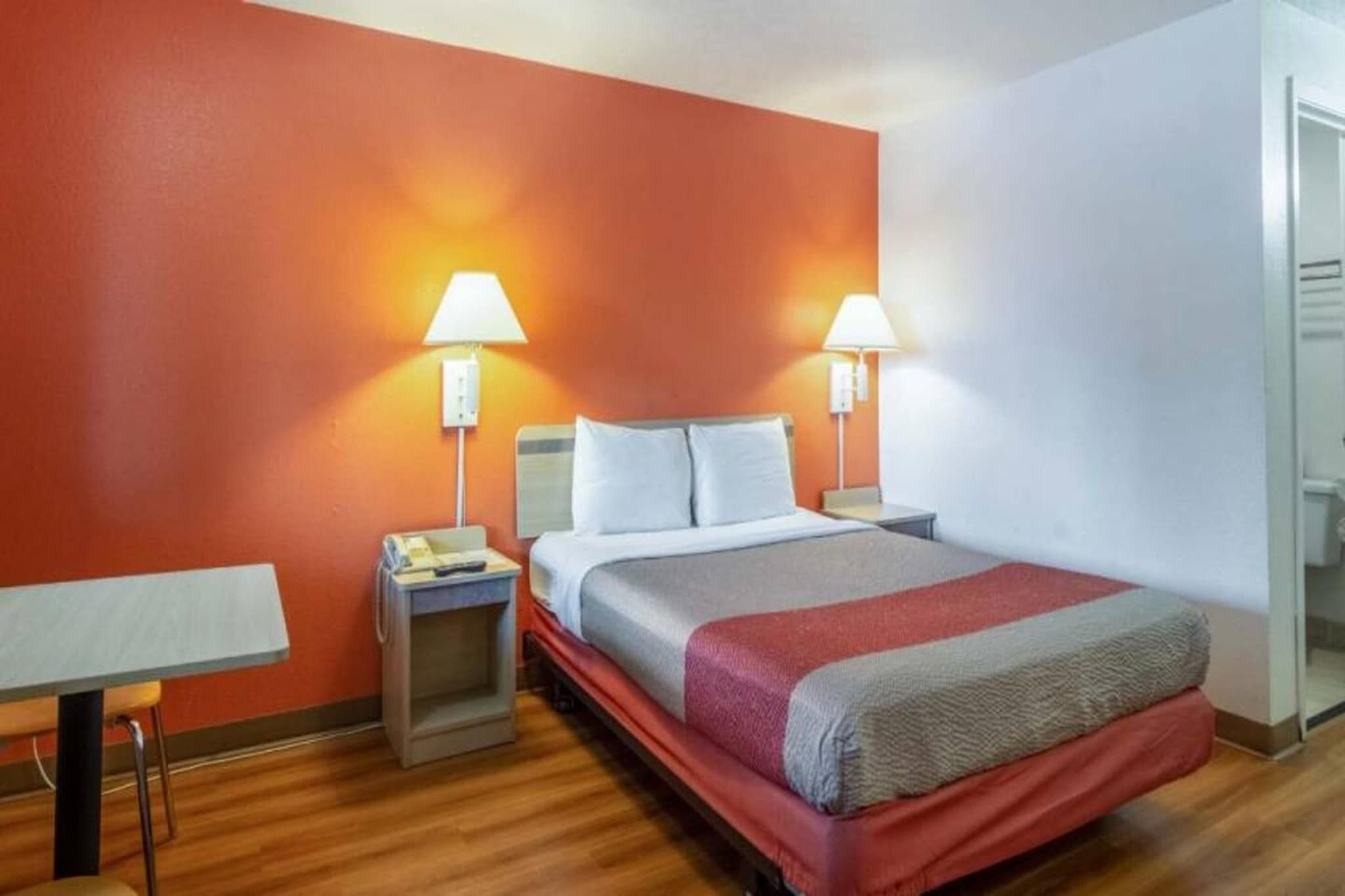Quarto de hotel com cama, mesas de cabeceira, escrivaninha e espelho.
