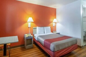 Une chambre d’hôtel avec un lit, des tables de chevet, un bureau et un miroir.
