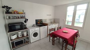 Eine kompakte Küche mit Waschmaschine, Mikrowelle und einem Essbereich mit Tisch und Stühlen.