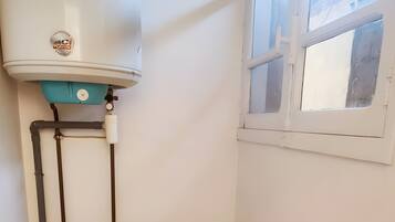 Un baño pequeño con inodoro, bidé, cubo de basura y ventana.