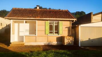 Una casa a un piano con tetto in tegole, una porta d'ingresso e una finestra con persiane.