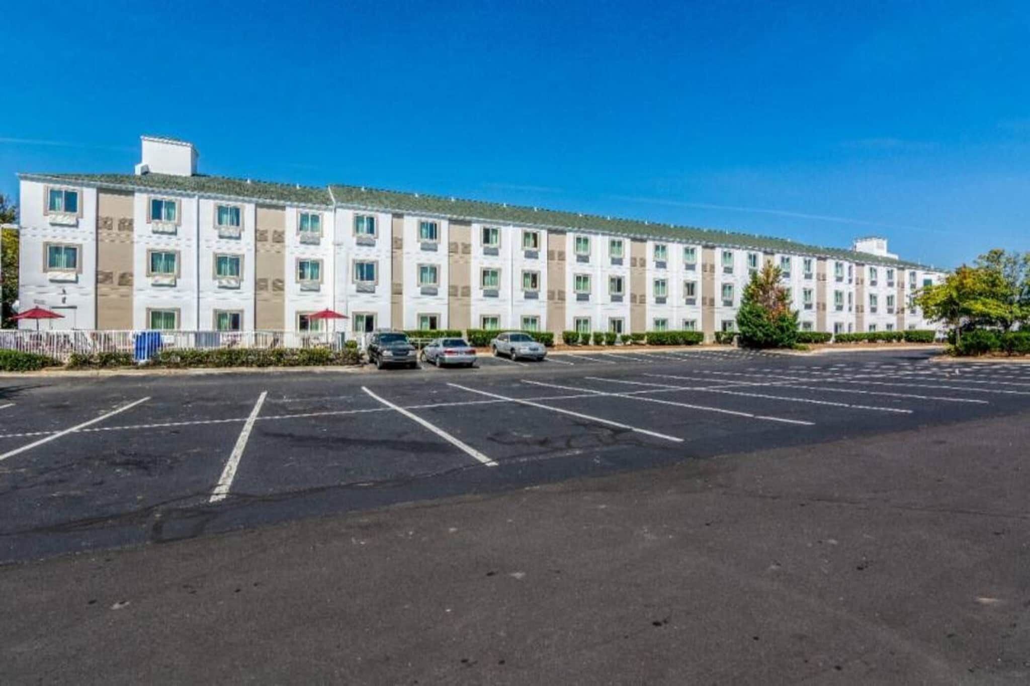 Een hotel met meerdere verdiepingen en een parkeerplaats ervoor.