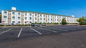 Een hotel met meerdere verdiepingen en een parkeerplaats ervoor.