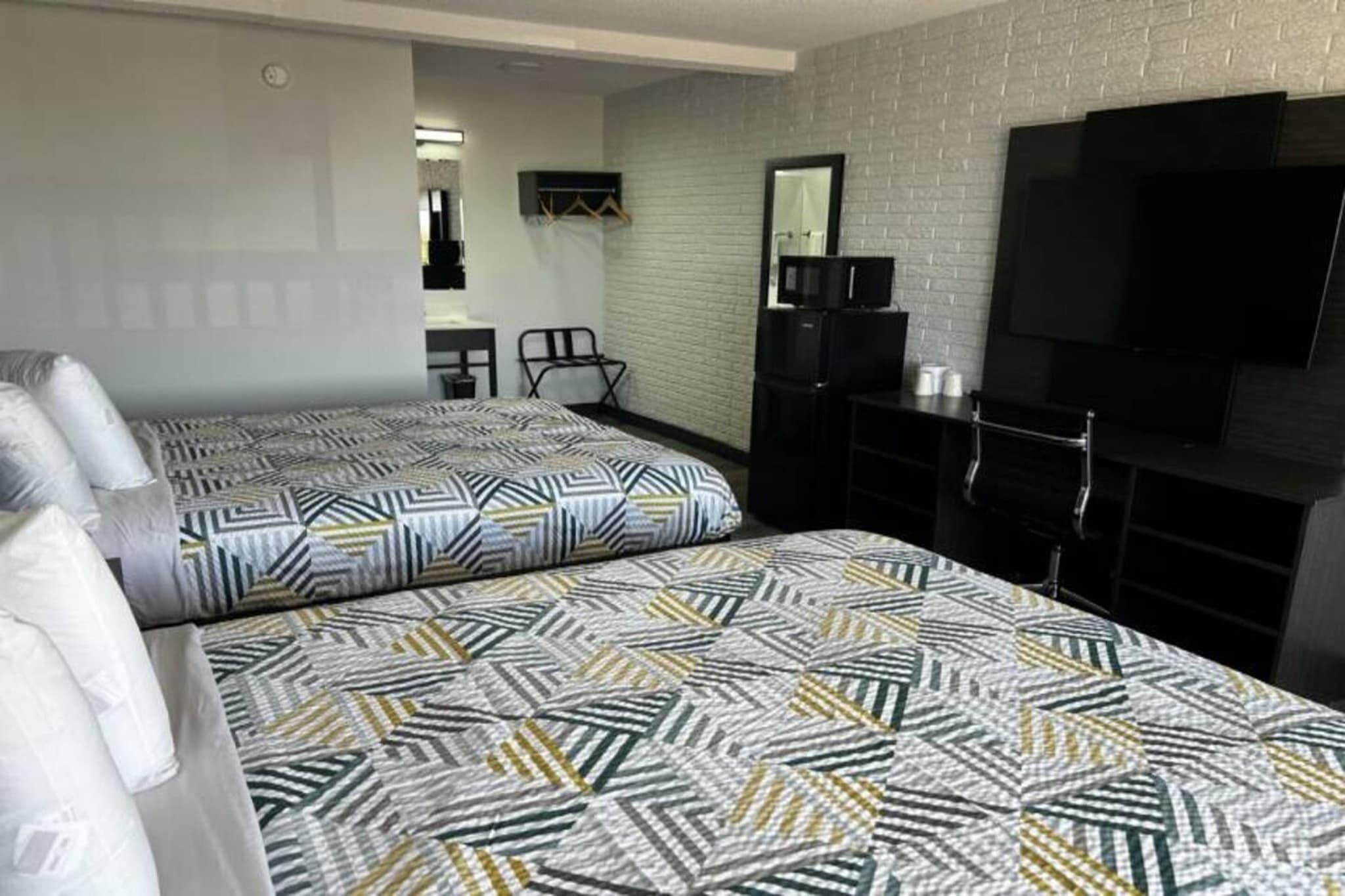Une chambre d’hôtel avec deux lits, une télévision, un bureau et une chaise.