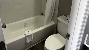Un baño con bañera, inodoro y cortina de ducha.
