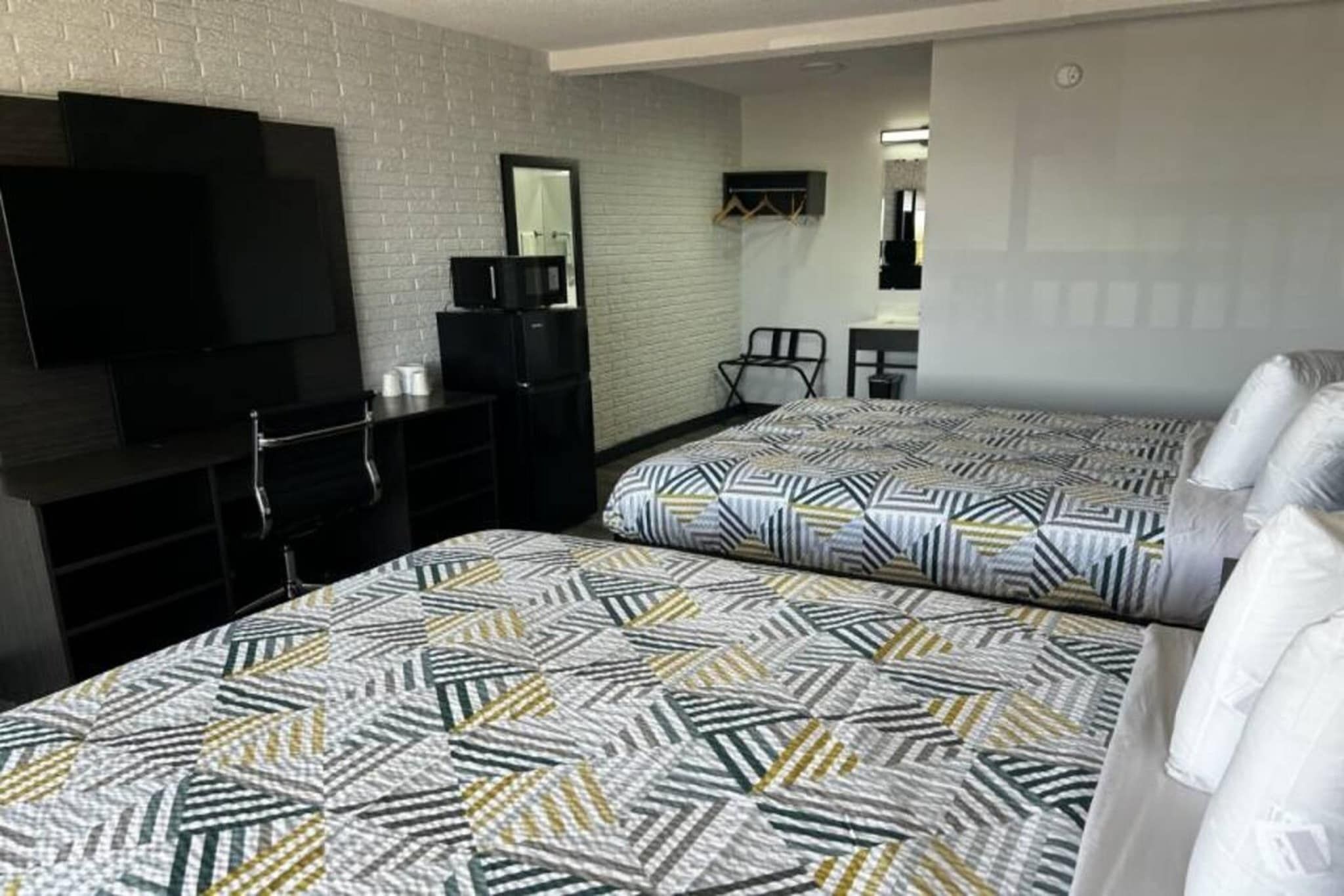 A hotel room with two beds, a TV, a desk, and a chair.