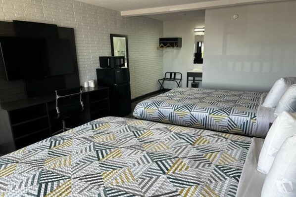 A hotel room with two beds, a TV, a desk, and a chair.