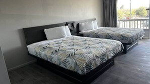 Habitación de hotel con dos camas, balcón y vistas al exterior.