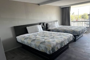 Ett hotellrum med två sängar, en balkong och utsikt över omgivningarna.