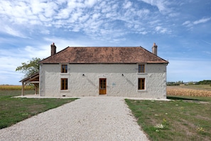 A two-story stone house with a gravel driveway and a wooden pergola on the left. - Vacation Home “La Ramellerie - Grange Arthuis” with Wi-Fi and Air Conditioning (Lavau)