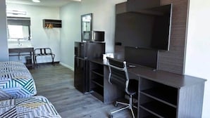 Un dormitorio moderno con cama, escritorio, silla, televisor y armario.