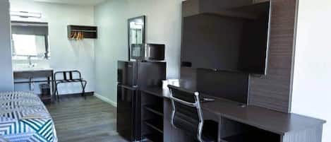 A modern bedroom with a bed, a desk, a chair, a TV, and a wardrobe.