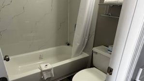 Un baño con bañera, inodoro y cortina de ducha.