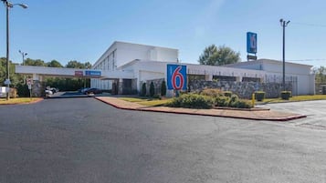 A 6-star hotel with a large parking lot and a clear sky.