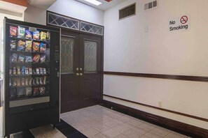 A hallway with a vending machine stocked with snacks and a 'No Smoking' sign on the wall. - 1 King Bed | Mobil Access Tub Nsmk Micfridg (Decatur GA)