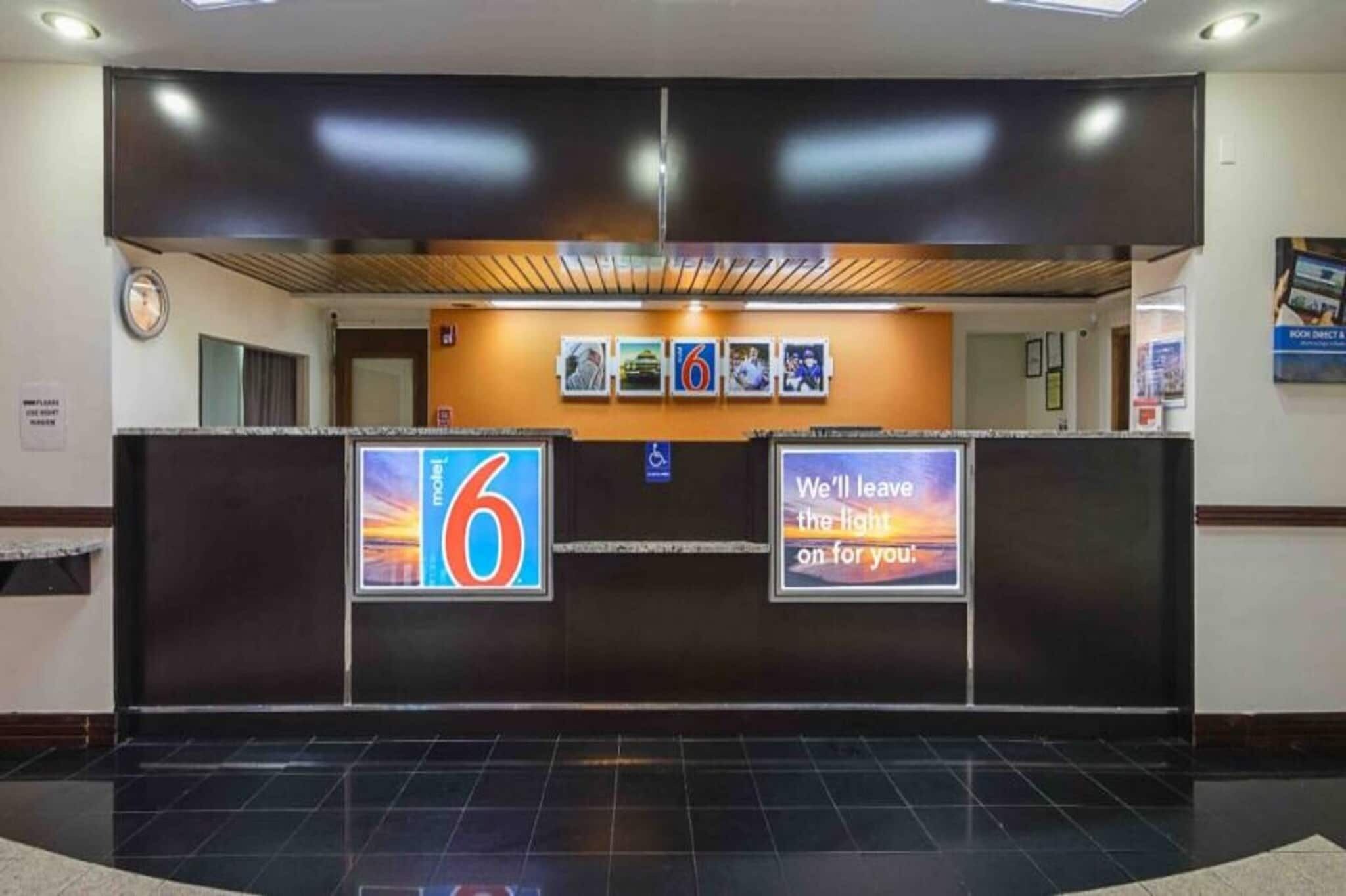 Un mostrador de recepción de hotel con pantalla digital y señal de accesibilidad para sillas de ruedas.