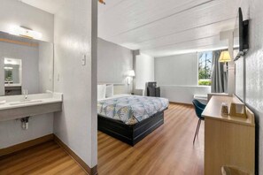 A modern hotel room with a bed, bedside table, chair, and a large window. - Comfy 1 King Bed | Non-Smoking, Micfridge (Decatur GA)