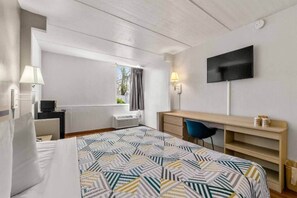A hotel room with a bed, a desk, a chair, a TV, and a window with curtains. - Comfy 1 King Bed | Non-Smoking, Micfridge (Decatur GA)