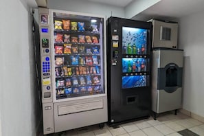 Une machine distributrice et un réfrigérateur se trouvent dans une pièce dont le sol est recouvert de carreaux.