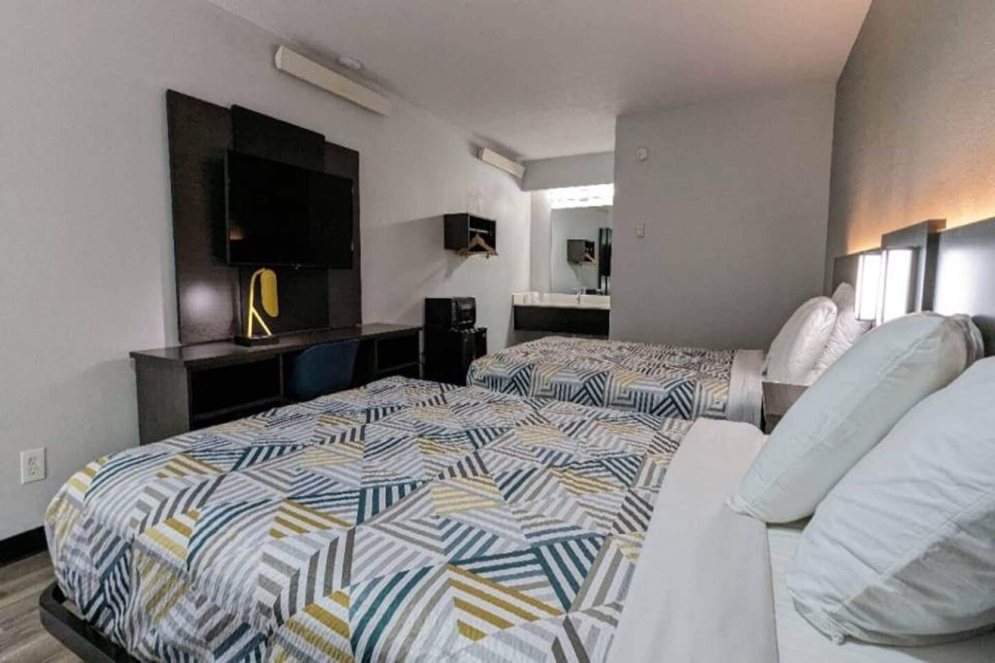 Een hotelkamer met twee bedden, een bureau, een stoel, een televisie en een spiegel.