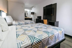Une chambre d’hôtel avec deux lits, un bureau, une chaise, une télévision et un miroir.
