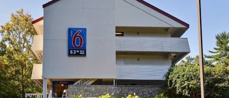 Ein modernes Gebäude mit einem Schild, das ein Motel namens '6' anzeigt, das eine Bewertung von 63 Punkten hat und WLAN anbietet.