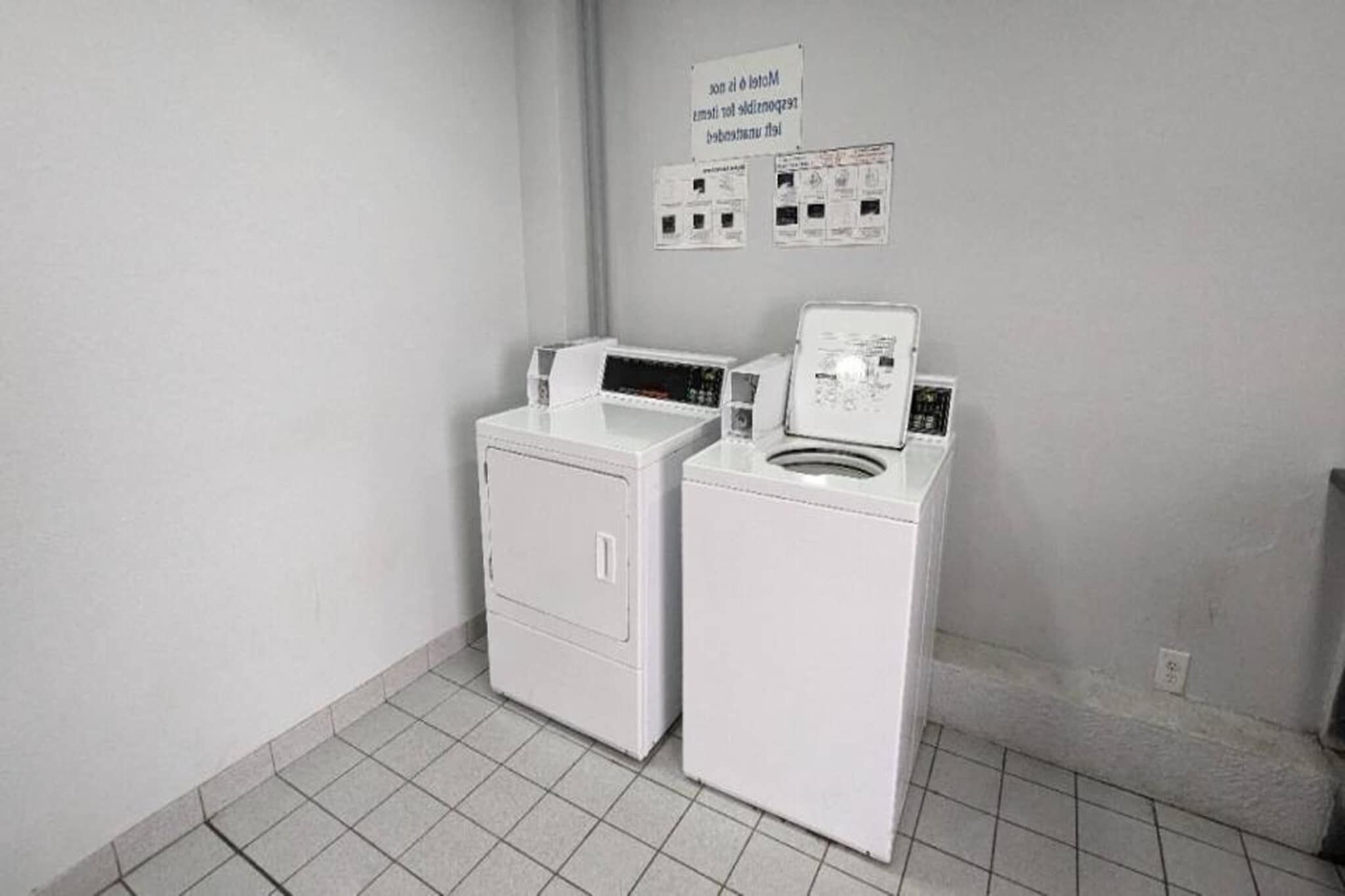 Uma lavanderia com duas máquinas de lavar roupa brancas e uma placa sobre elas.