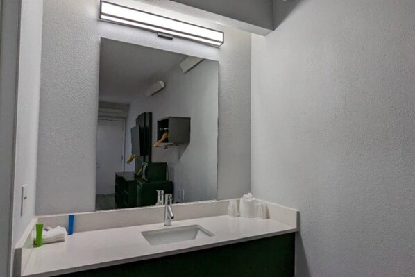 Un baño con un lavamanos blanco, un espejo y un armario verde.